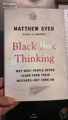 a person holding up a book about black box thinking