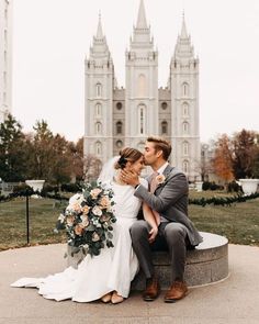 a bride and groom sitting on a stone bench in front of the salt lake temple