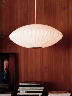 a white light hanging from a wooden wall next to books and a framed photograph on a shelf