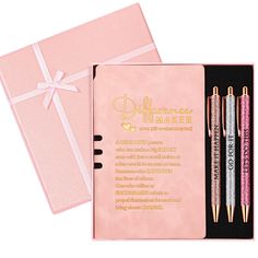 two pens in a pink gift box with a notepad and pen next to it