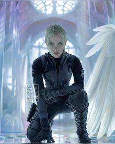 a woman with white hair and black leather outfit kneeling in front of an angel statue