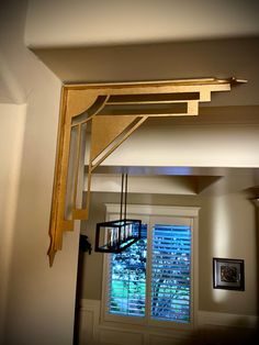 the light fixture is hanging from the ceiling above the window in the room with the shutters open