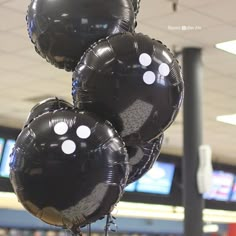 three black balloons with white polka dots are hanging from a pole in an airport lobby