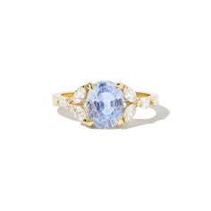 an oval blue and white sapphire ring with three diamonds on the sides, set in yellow gold