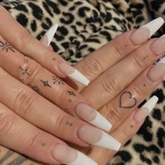 two hands with different designs on them and one has a heart tattoo on the middle finger