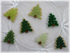 beaded christmas trees are arranged on a white doily with green and gold trimmings