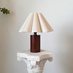 a lamp sitting on top of a white table next to a planter and wall