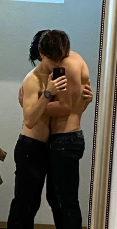 a man taking a selfie in front of a mirror with his shirtless body