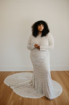 a woman in a white dress standing on a wooden floor with her arms folded up