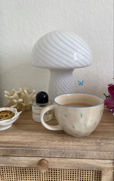 a cup of coffee sitting on top of a wooden table next to a mushroom lamp