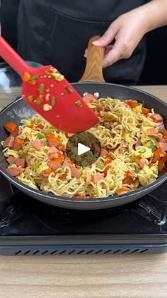 a person cooking food in a skillet on top of a stove with a spatula