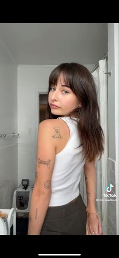 a woman with tattoos standing in a bathroom