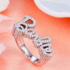 Elevate your style with our stunning 925 sterling silver Barbie ring. This exquisite piece features the word “Barbie” elegantly crafted in sparkling gemstones, creating a dazzling and glamorous accessory perfect for any fashion-forward individual. The ring’s intricate design and shimmering details make it a standout piece in any jewelry collection. Shipping:Takes 5-8 business days depending on stock, these beautiful rings are custom sized and made in small batches. If your size is in stock this item will ship immediately Product Details: Material: 925 Sterling Silver Gemstones: Clear Cubic Zirconia Design: Sparkling “Barbie” lettering Finish: Polished Size: Adjustable Occasion: Everyday wear, parties, and special occasions Why Choose This Ring? Elegance: The combination of sterling silver Luxury Sparkling Rings For Party, Dazzling Sterling Silver Promise Rings, Elegant Sparkling Crystal Promise Ring, Party Rings With Pave Setting In Diamond White, Vs Clarity Cubic Zirconia Initial Ring For Promise, Luxury Sparkling Party Rings, Dazzling Sterling Silver Jewelry For Promise, Party Jewelry With Pave Setting And Cubic Zirconia, Dazzling Silver Jewelry For Promise