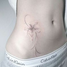 a woman's stomach with a flower tattoo on her lower back and the words calvin klein written below it