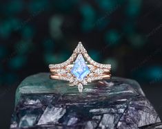 an engagement ring with a pear shaped blue topazte surrounded by diamonds on a rock