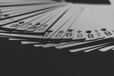 a pile of playing cards sitting next to each other on top of a table in black and white