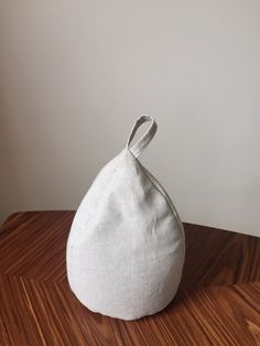 a small white bag sitting on top of a wooden table next to a wall and floor