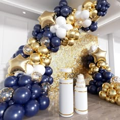 an arch made out of balloons and confetti is shown in this room with gold, white and blue decorations