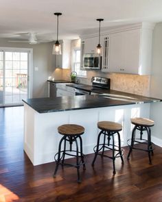 a kitchen with three stools and an island