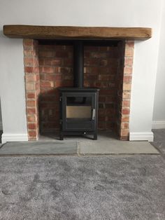 a wood burning stove sitting inside of a brick fireplace