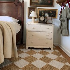 a bed room with a neatly made bed next to a dresser and a painting on the wall