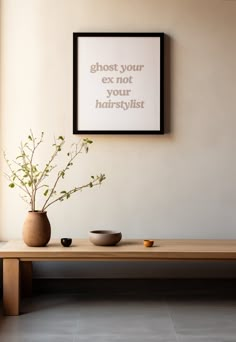 a table with two bowls and a plant on it in front of a framed poster