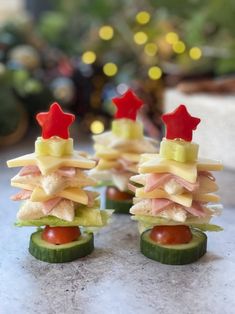 small sandwiches are arranged in the shape of christmas trees on cucumbers and tomato slices