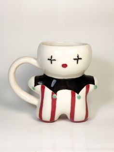 a white ceramic cup with a black and red striped design on the bottom, holding a smaller mug