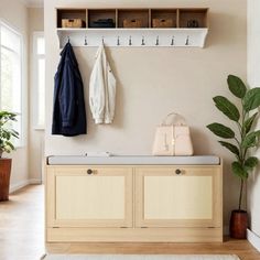 a coat rack and bench in a white room with potted plants on the wall