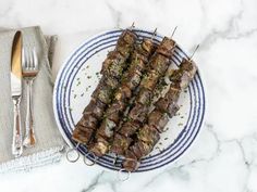 skewered meat on a blue and white plate next to silverware