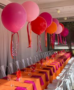 the tables are set with orange and pink tablecloths, white chairs, and balloons