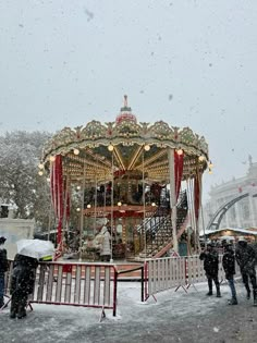 a merry go round in the snow with people standing around