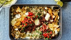 a tray filled with nachos and salsa on top of a blue table cloth