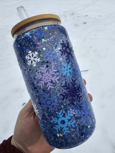 someone is holding up a blue glittered can with snowflakes on it