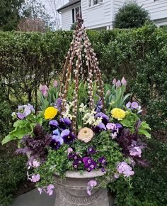 a large flower pot filled with lots of purple and yellow flowers in front of a house