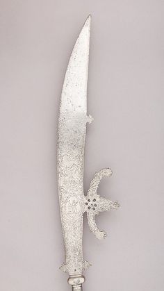 an ornate silver knife is on display against a gray background