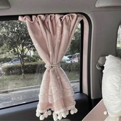 the interior of a car with pink curtains and pom poms