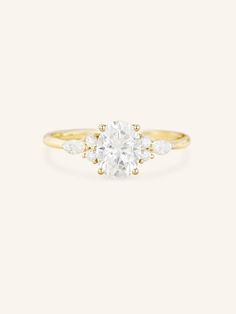 a yellow gold ring with an oval cut diamond and three small white diamonds on the band