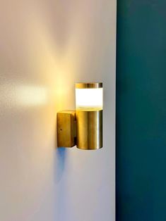 a wall mounted light on the side of a white wall next to a blue wall