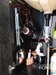 Red circles mark where black cup hooks are placed inside of the bathroom cabinet for hanging flat iron, hair dryer and mirror under the bathroom sink.