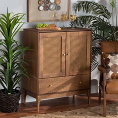 a wooden cabinet sitting next to a chair and potted plant in a living room