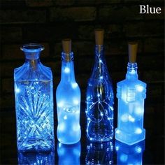 three bottles with lights in them sitting on a table