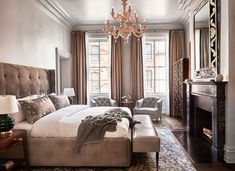 a bedroom with a large bed, chair and chandelier hanging from the ceiling