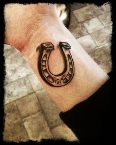 a man's wrist with a horseshoe tattoo on it