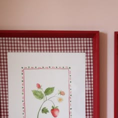 two framed pictures with strawberries and leaves on them, one is red and the other is white