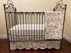 an iron crib with a white sheet and flowered bedding on the bottom