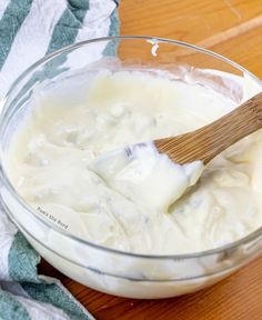 a wooden spoon in a glass bowl filled with white liquid on top of a table