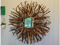 a mirror hanging on the side of a white wall next to a wooden stick wreath