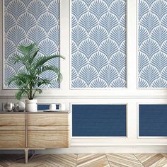 a plant is sitting on a dresser in front of two wall panels with blue and white designs