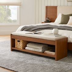 a bed sitting on top of a wooden floor next to a white rug and window